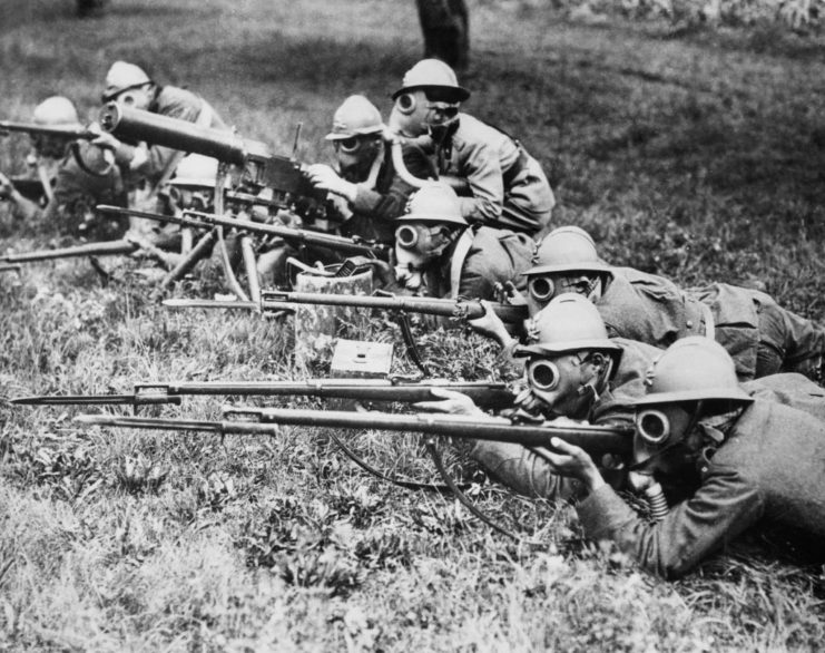 Italian soldiers in gas masks lying on the ground while aiming their M91 Carcanos