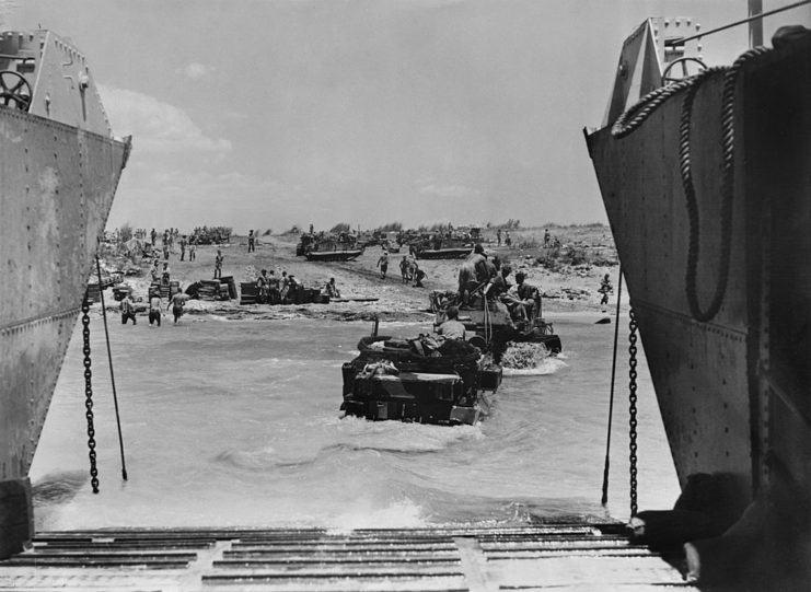 Armored vehicles being towed ashore from a landing craft