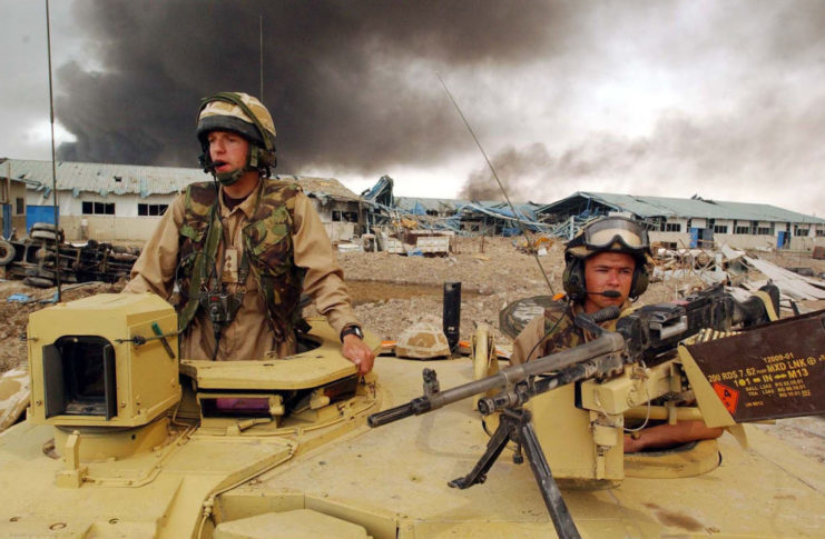 Two British soldiers standing halfway out of the top of a tank