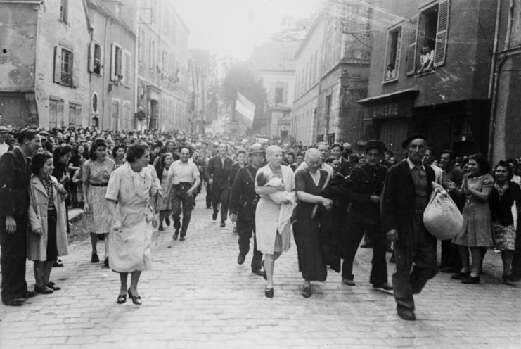 Crowd gathered around a group of women walking down a street