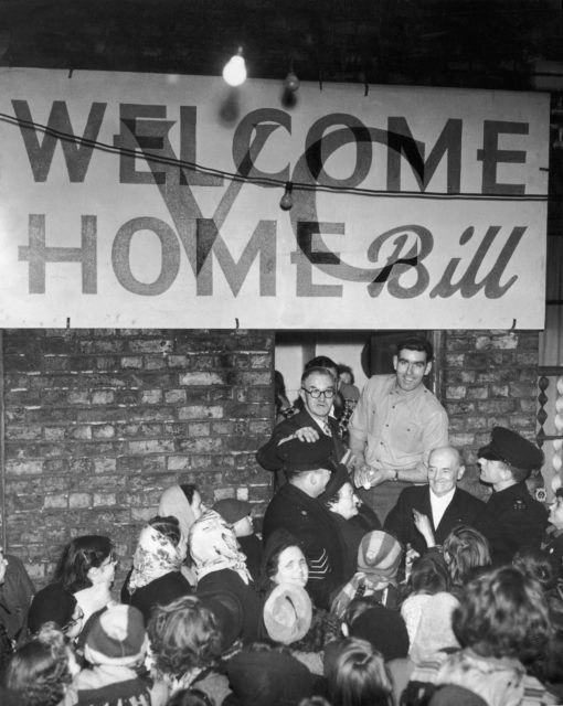 Crowd gathered behind a sign reading "WELCOME HOME Bill"
