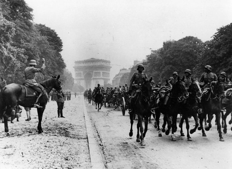 German artillerymen riding horses down a street