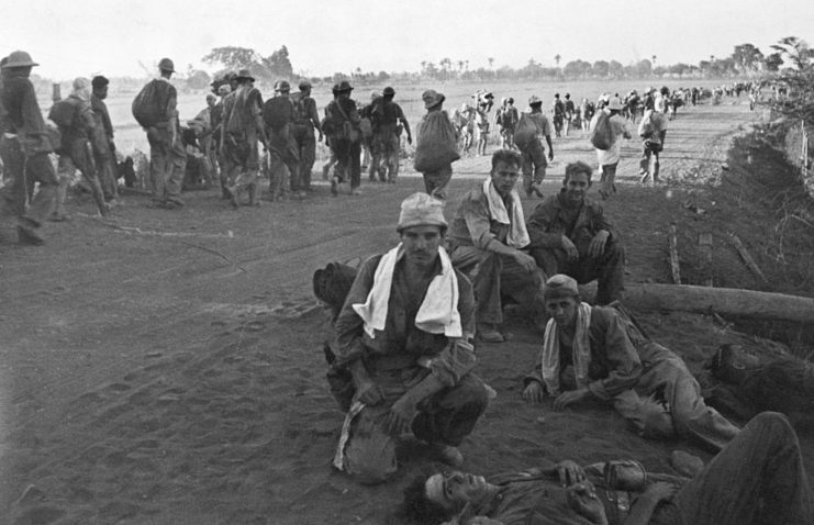 American soldiers walking in a line and sitting on the ground