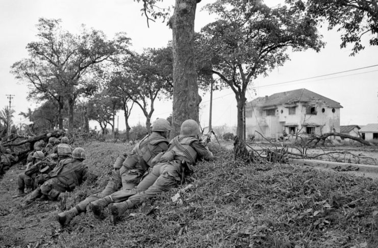 US Marines lying along the side of a road