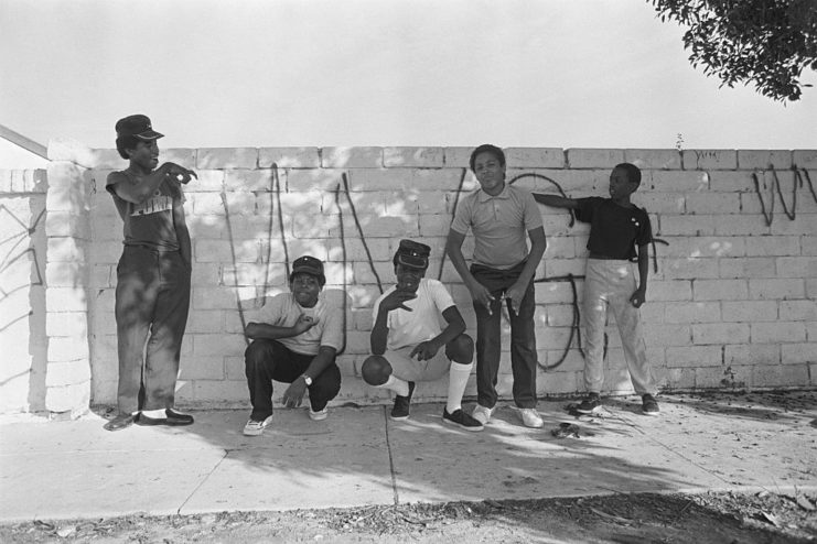 Five members of the Crips standing in front of a brick wall
