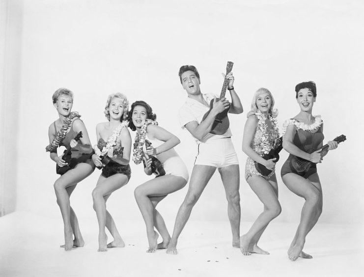 Elvis Presley and five female dancers playing the Ukulele