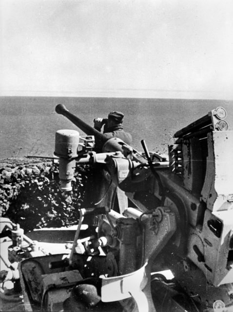 German soldier looking out over the water with binoculars