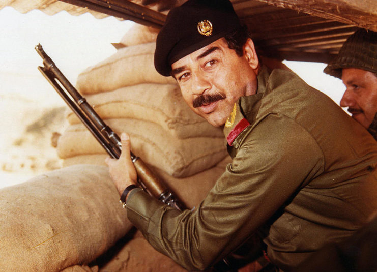 Saddam Hussein holding a firearm