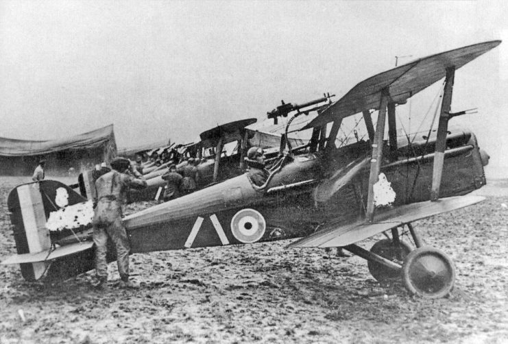 Man standing at the tail end of a Royal Aircraft Factory S.E.5 biplane