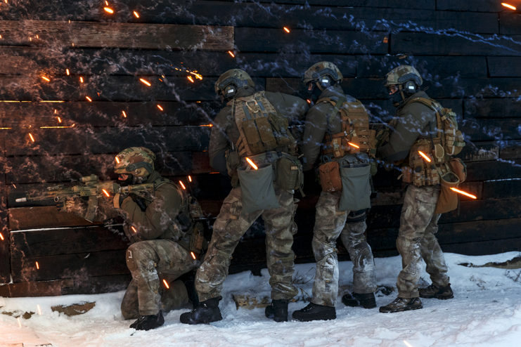 Four Russian Spetsnaz officers crouched behind a wooden wall