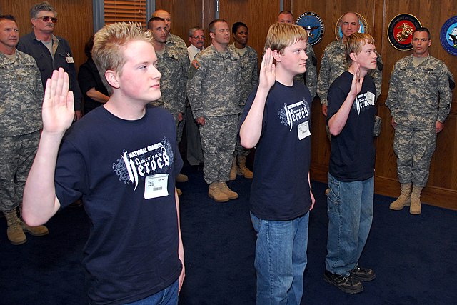 Three US Army recruits holding their hands up for the oath of enlistment