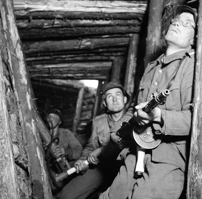 Finish soldiers holding firearms while hiding in a wooden fortification
