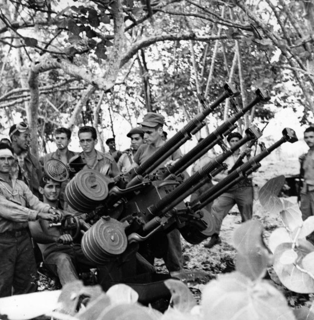 Cuban militia members standing behind a large gun