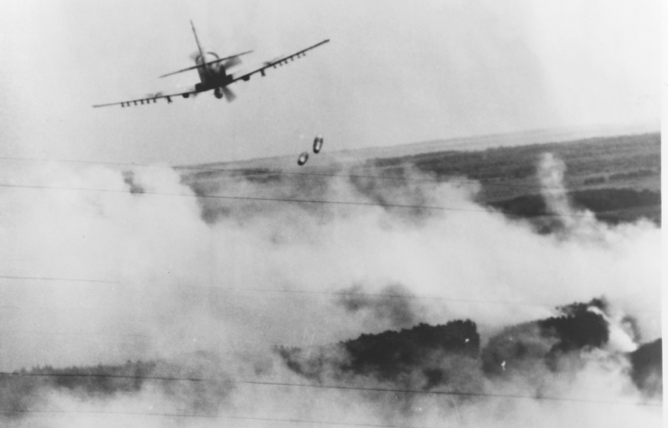 An A-1 Skyraider drops two bombs over the smoky Vietnam hillside