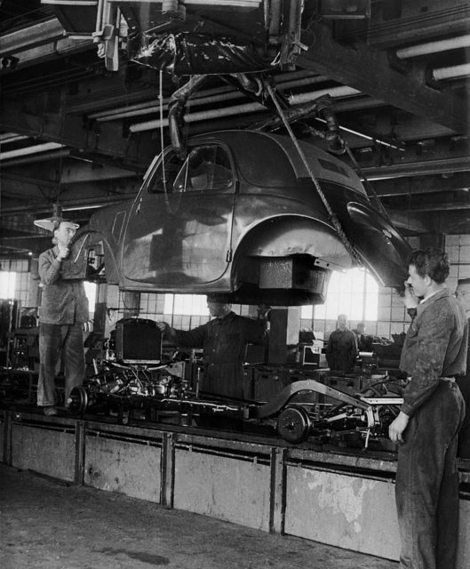 Factory workers standing around the body of a FIAT car