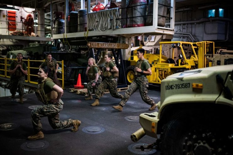 Female Engagement Team members performing stretches among a series of vehicles