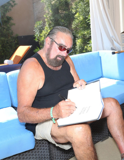 Richard Marcinko sitting down while signing a copy of his book