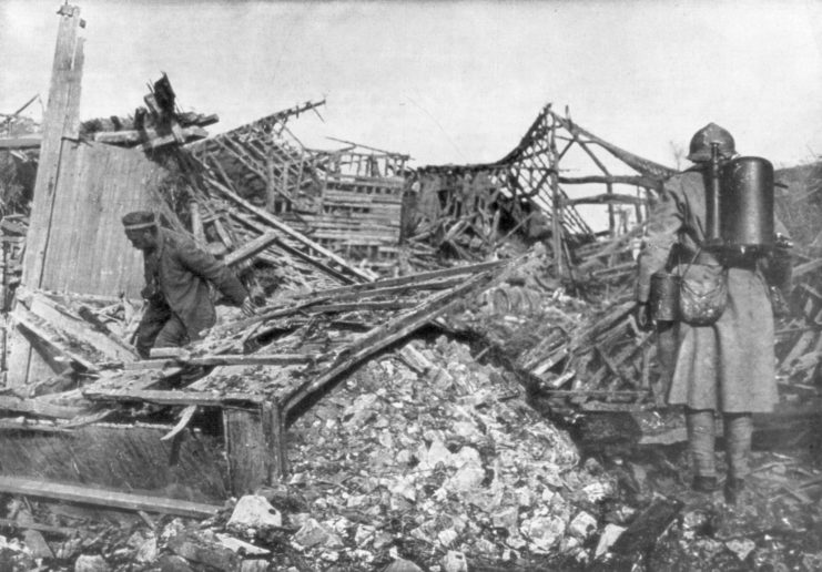 French soldiers standing with flamethrowers among the remains of a damaged building