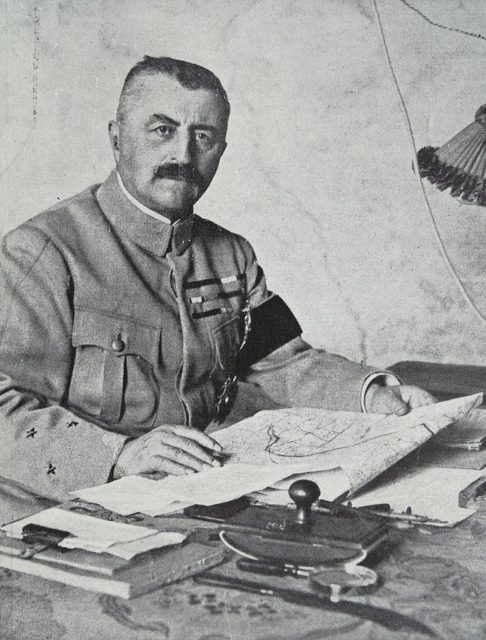 Louis Francois d'Esperey holding a map while sitting at a desk