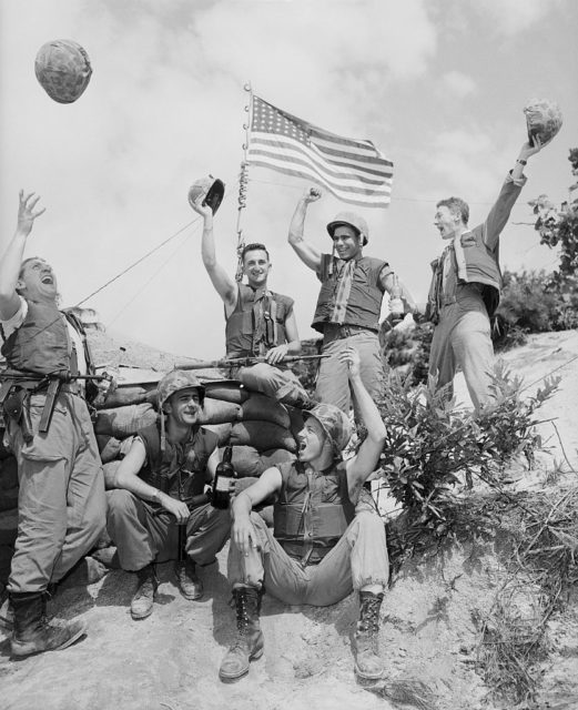 US soldiers celebrating in front of the American flag