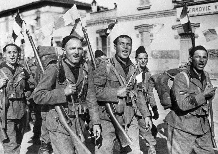 Italian soldiers marching together with flags tied to their bayonets