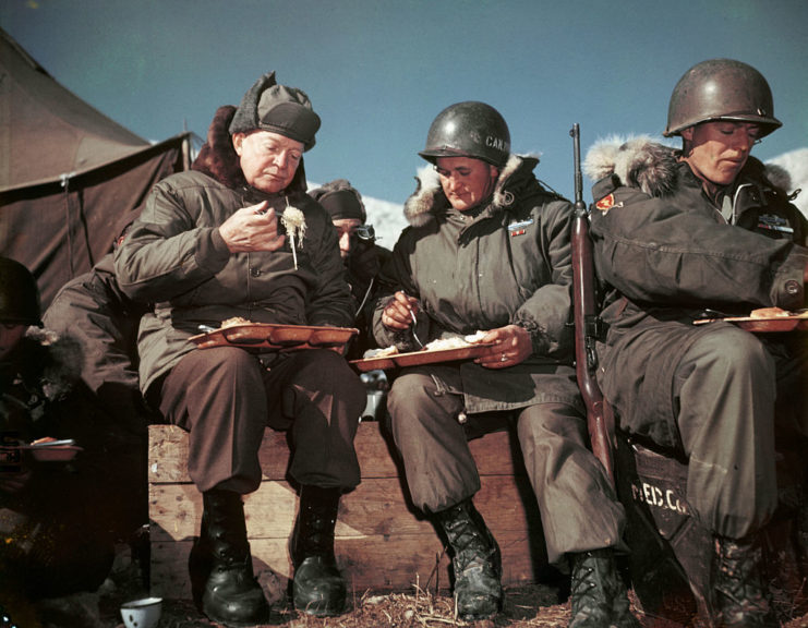 Eisenhower eating a meal with two members of the US military