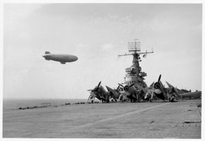 Blimp flying over an aircraft carrier