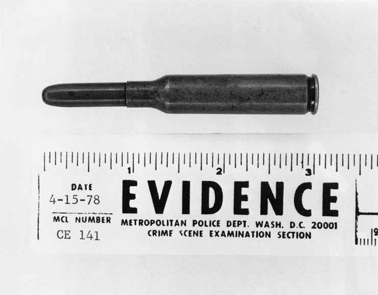 Unfired cartridge measured against a ruler with the word "EVIDENCE" stamped on it