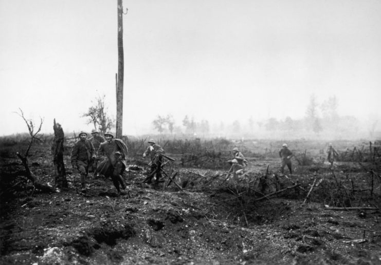 Italian soldiers running through a field that's been destroyed by fighting