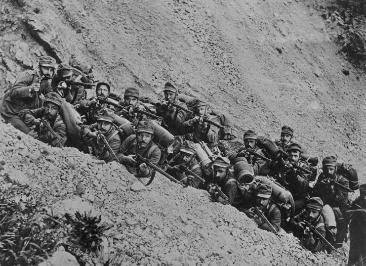 Italian soldiers aiming their weapons while standing in a hillside trench