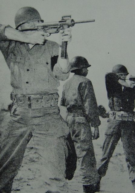 Two soldiers aiming M3 "Grease Guns" while another watches