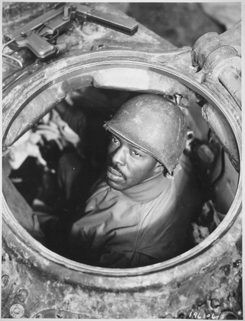 Cpl. Carlton Chapman sticking his head out of the top of a tank