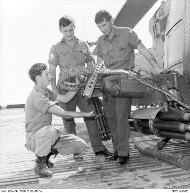 Three Australian servicemen standing around an M134 Minigun