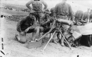 Soldiers standing behind an early machine gun