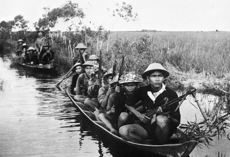 Viet Cong guerrillas riding down a river in boats