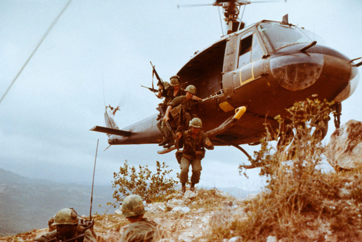 Infantrymen jumping from a hovering Bell UH-1 Iroquois "Huey" helicopter