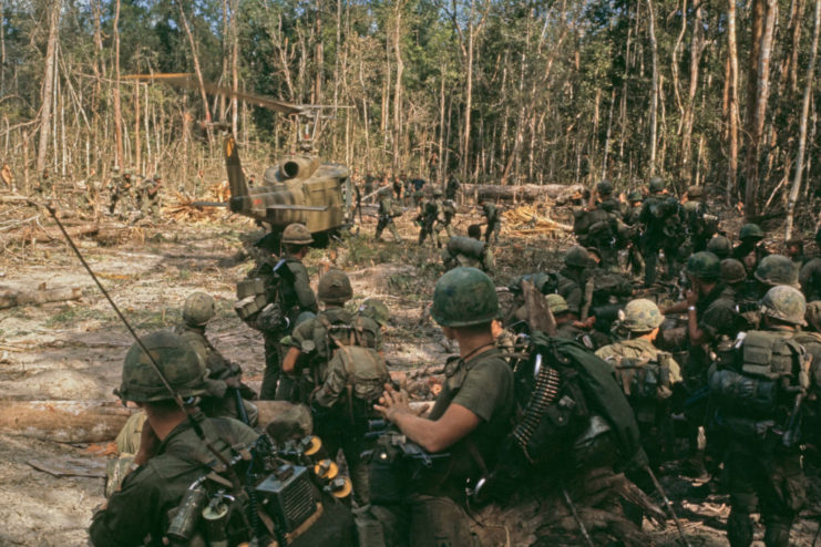 Members of the 1st Cavalry Division standing around a grounded Bell UH-1 Iroquois