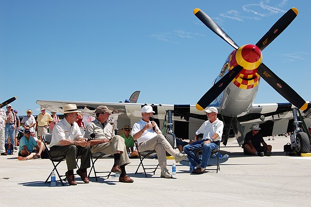 Clarence "Bud" Anderson sitting with three others in front of his North American P-51D Mustang 'Old Crow'