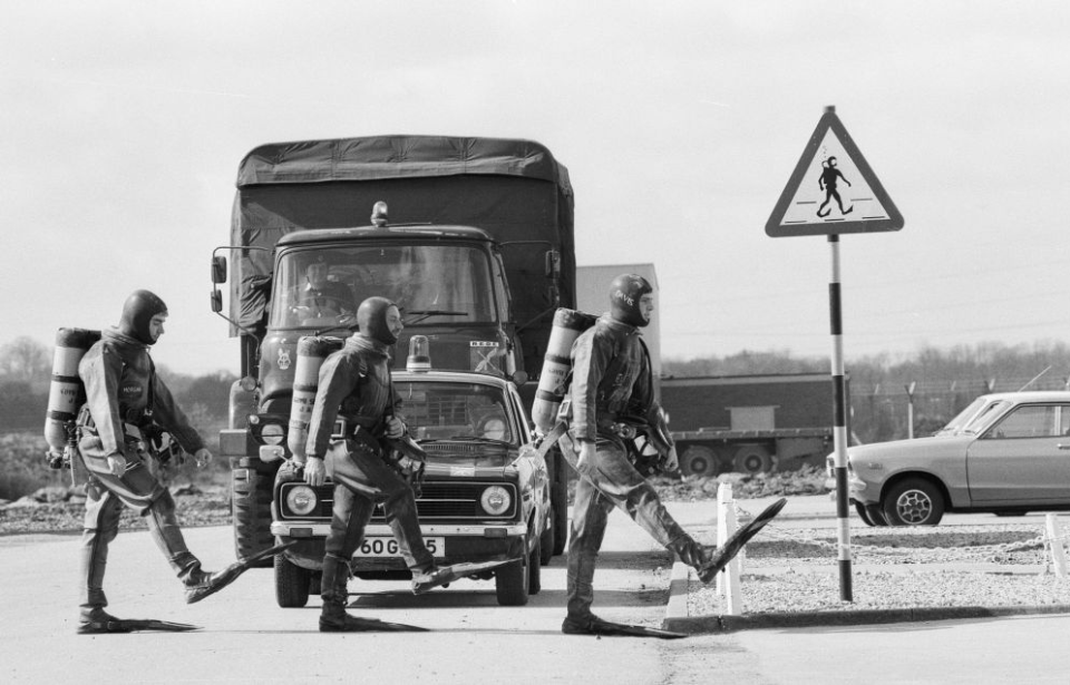 Three Frogmen walking in front of a stopped truck