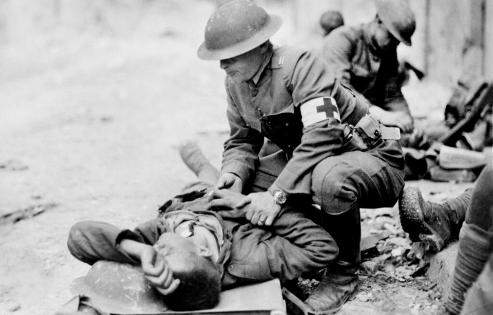 Soldiers kneeling over an injured comrade on the battlefield