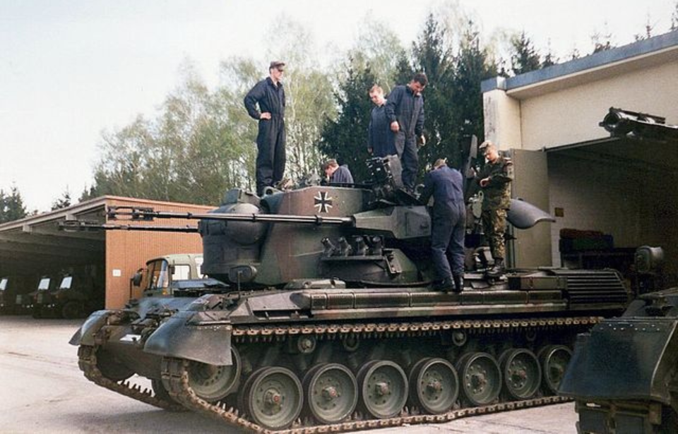 Five German soldiers standing on top of a Flakpanzer Gepard