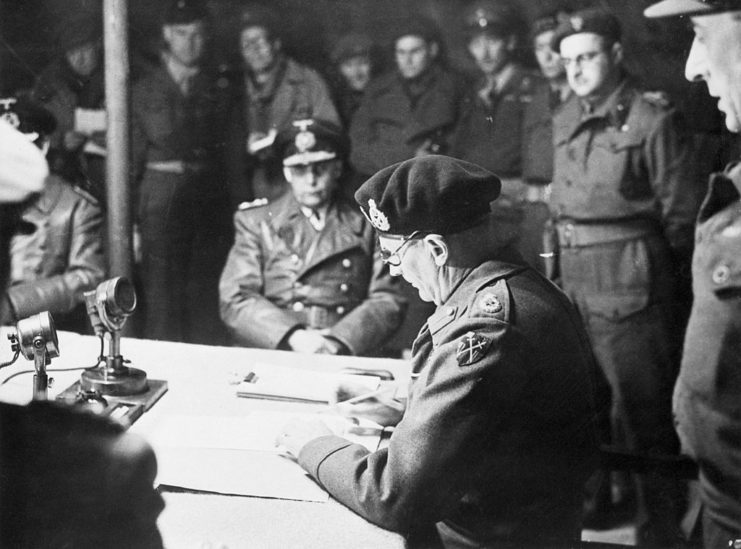 Bernard Montgomery signing the German unconditional surrender while military officials watch