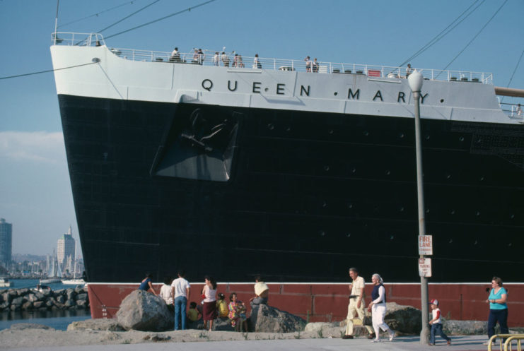 Des passants devant le RMS Queen Mary alors qu'il est amarré