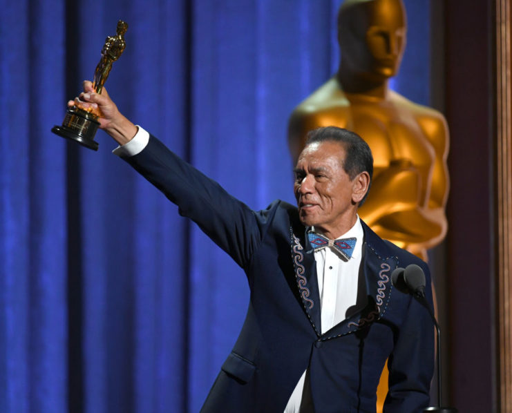 Wes Studi holding up his Academy Award