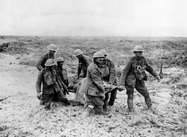 Stretcher-bearers carrying a wounded soldier through deep mud