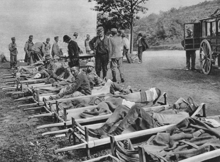 Austrian soldiers lying on stretchers outside of a field hospital