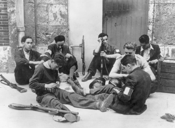 Free French members sitting on the ground with their firearms