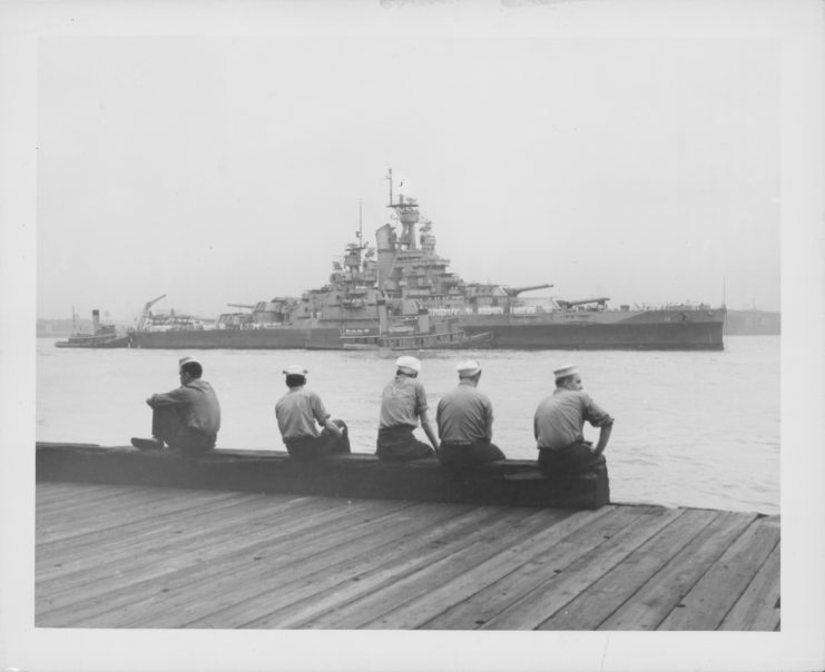 Five sailors watching the USS Nevada (BB-36) sail by