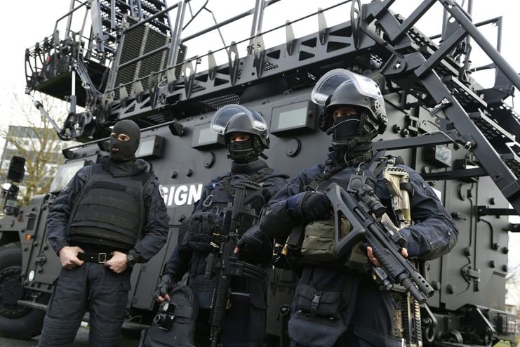 Three GIGN members standing outside an armored vehicle