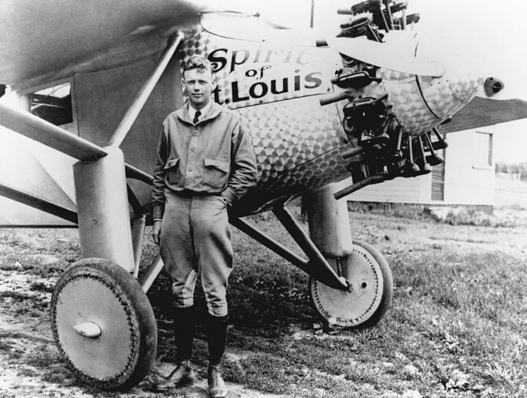Charles Lindbergh standing in front of the "Spirit of St. Louis"